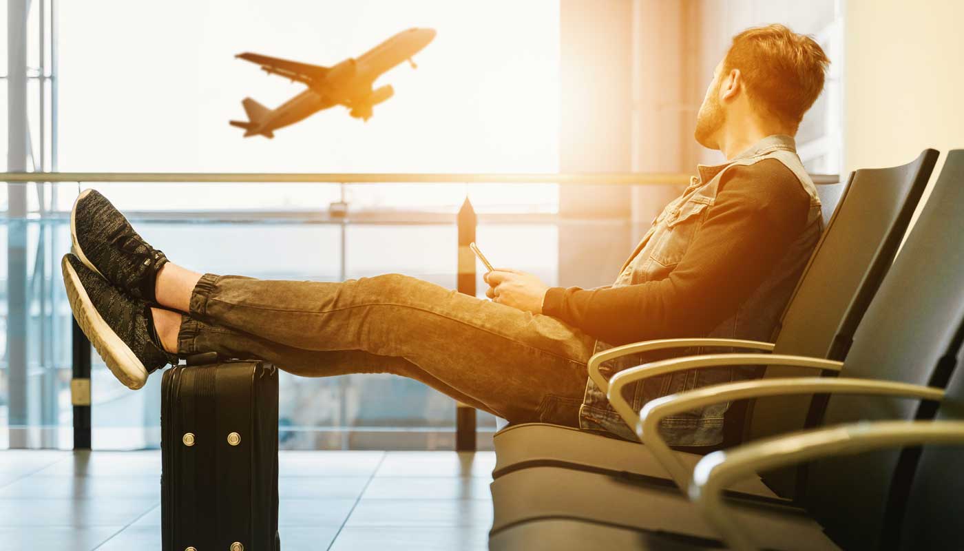 Zanzibar Experts Homme assis sur une chaise avec des pieds en haut d'un aéroport avec un avion décollant en arrière-plan